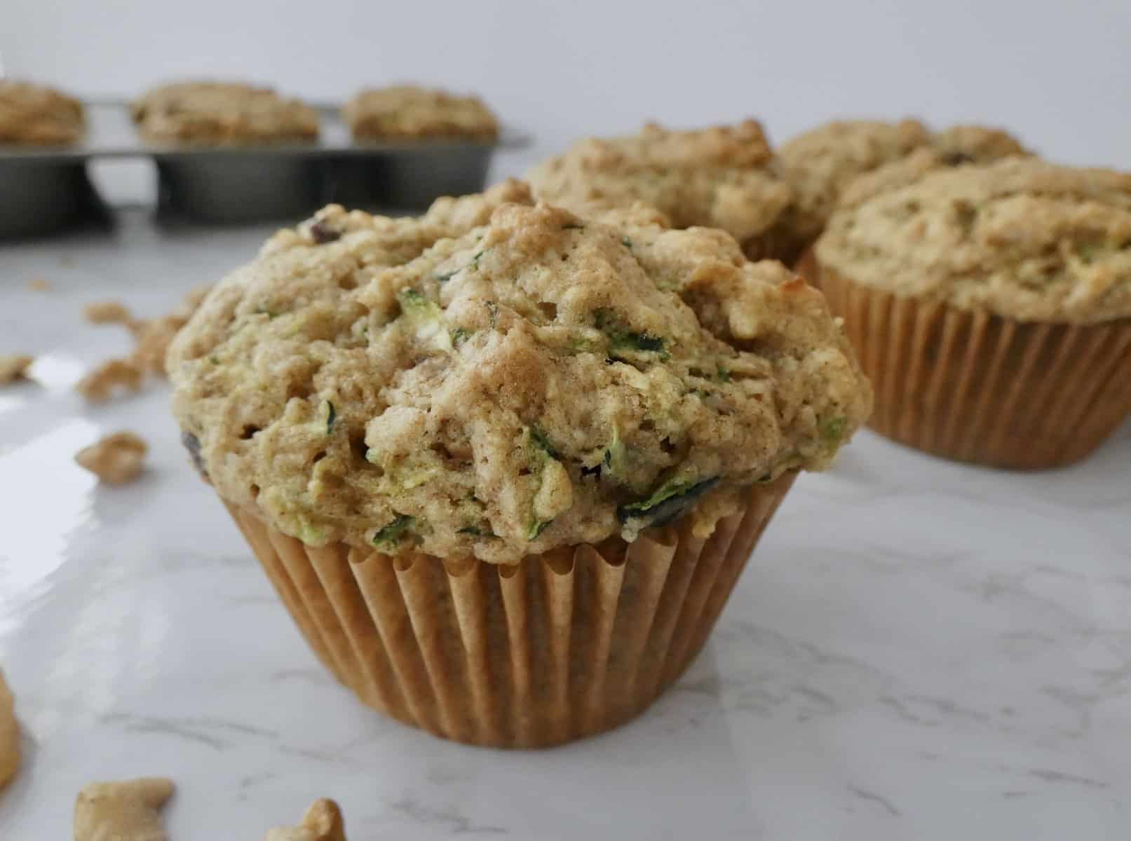 Bakery style zucchini muffins in front of muffin tin