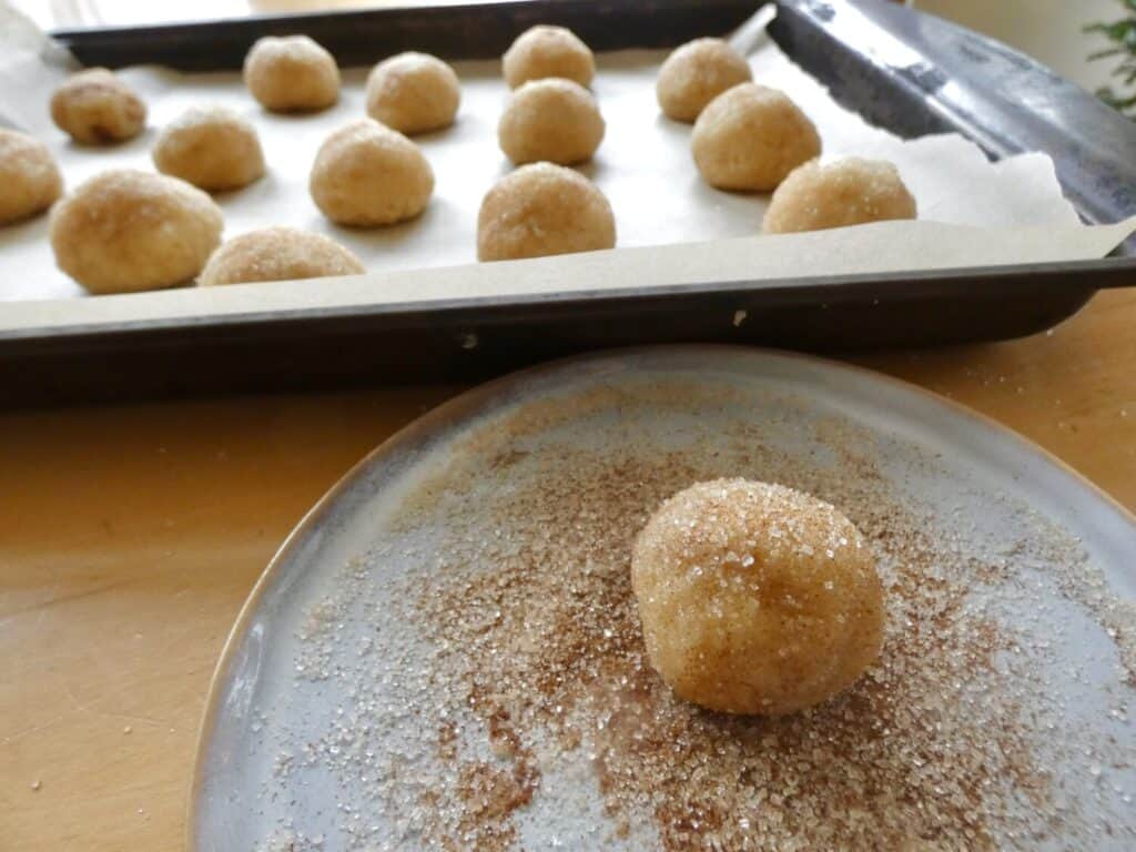 rolling the snickerdoodle amaretti cookie balls in cinnamon sugar