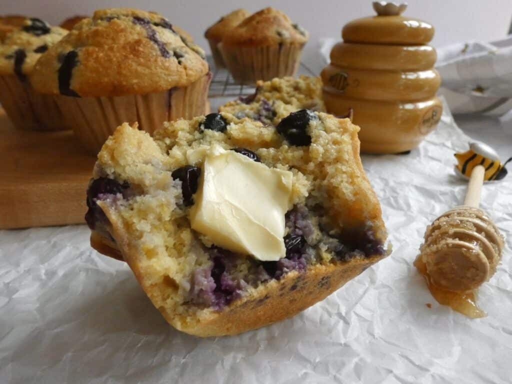 blueberry cornbread muffin with slice of butter and honey dipper