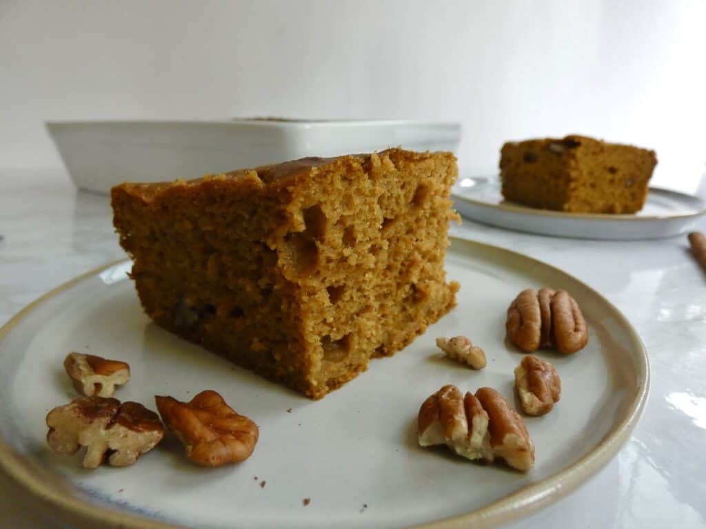 Slice of simple sourdough discard pumpkin cake on a plate with pecans