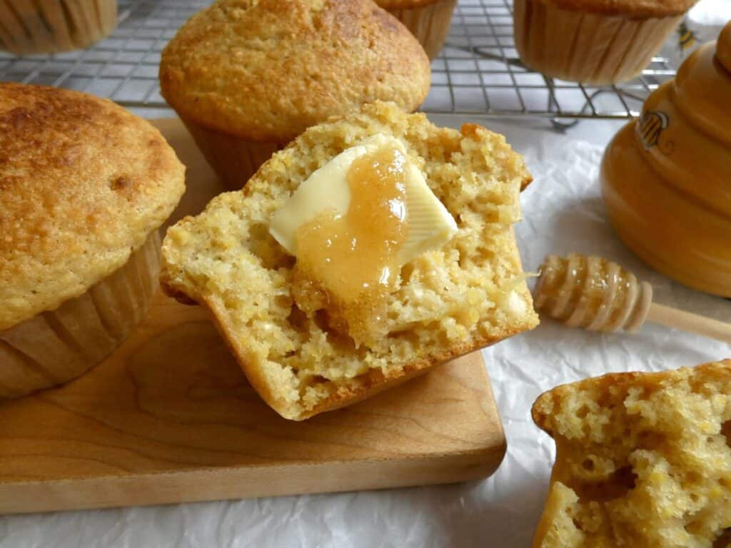 bakery style cornbread muffin with slice of butter and drizzle of honey