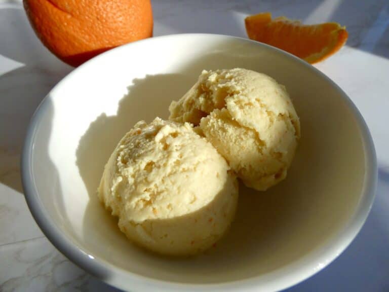 two scoops of creamy homemade orange ice cream in a bowl