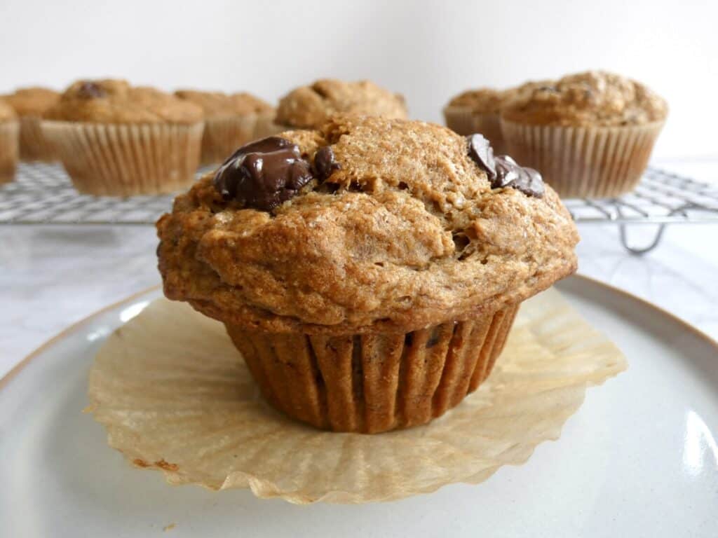 close up of healthier chocolate chip banana muffin on paper liner