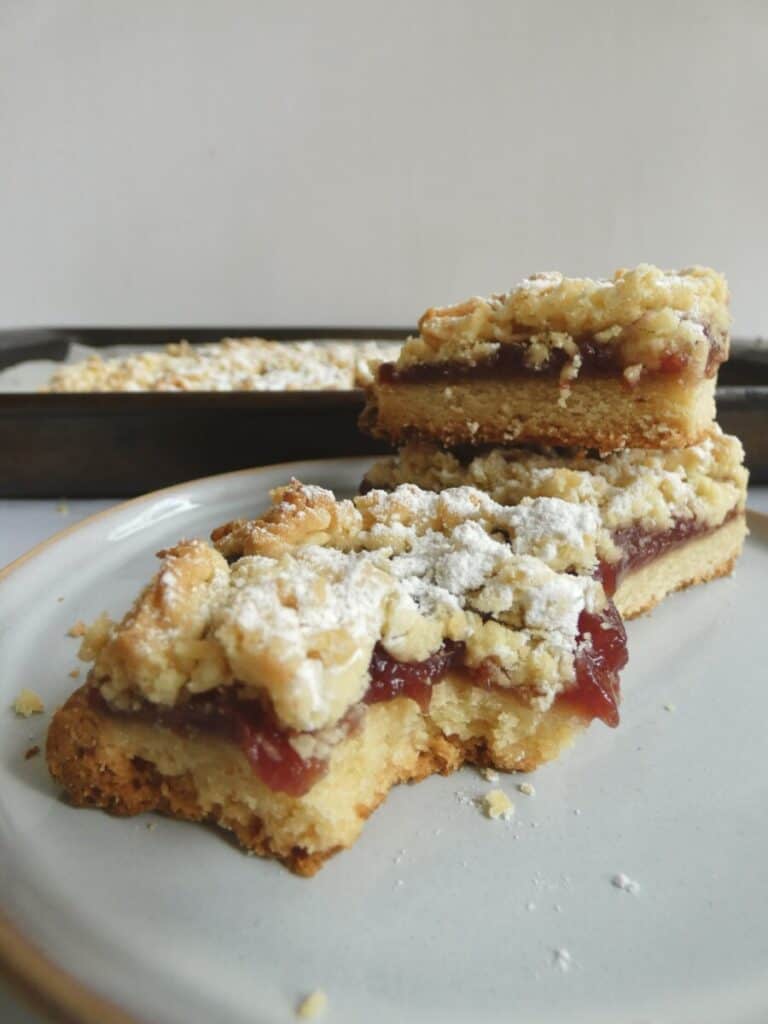 vertical close up of raspberry crumb bar with missing bite