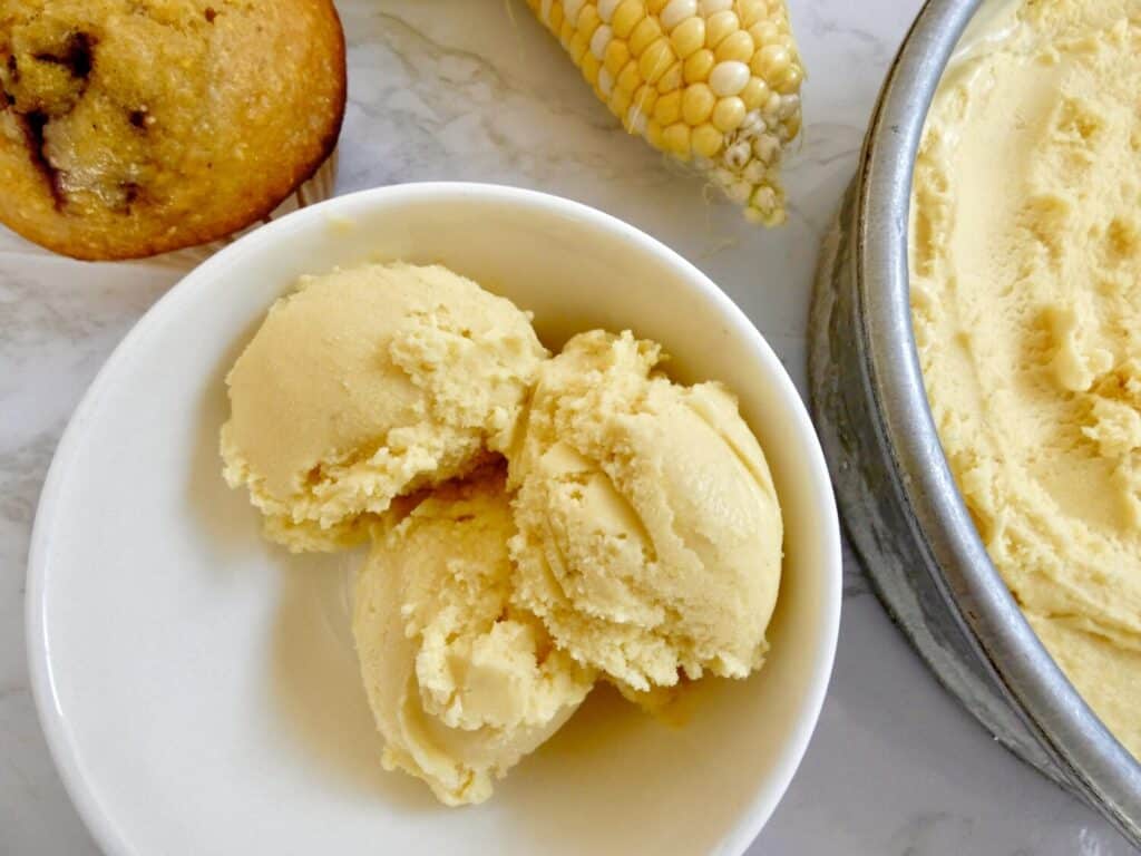 bowl with three scoops of sweet corn ice cream and ear of corn in the background