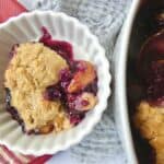 bowl of healthier blueberry peach cobbler with baking dish