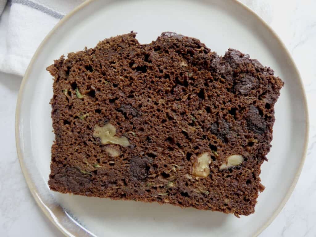 close up of a slice of healthier double chocolate zucchini bread on round plate