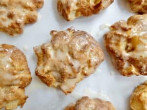 air fryer apple fritters with vanilla icing on parchment paper