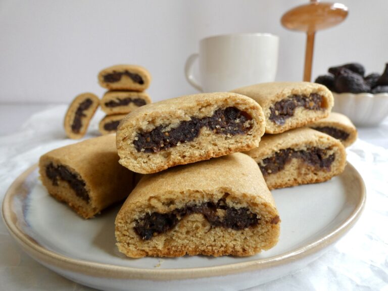 close up of Healthy Homemade Fig Newtons on a round plate with a bowl of dried figs in the background