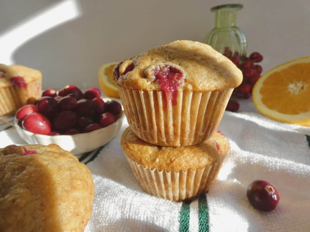 stack of Cranberry Orange Muffins next to a bowl of fresh cranberries