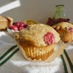 Cranberry Orange muffin on top of paper liner with fresh cranberries in the background